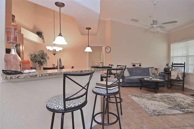 kitchen featuring light tile floors, ceiling fan with notable chandelier, ornamental molding, a breakfast bar area, and light stone counters