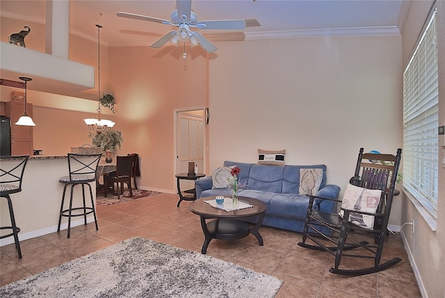 living room featuring crown molding, ceiling fan with notable chandelier, light tile floors, and a high ceiling