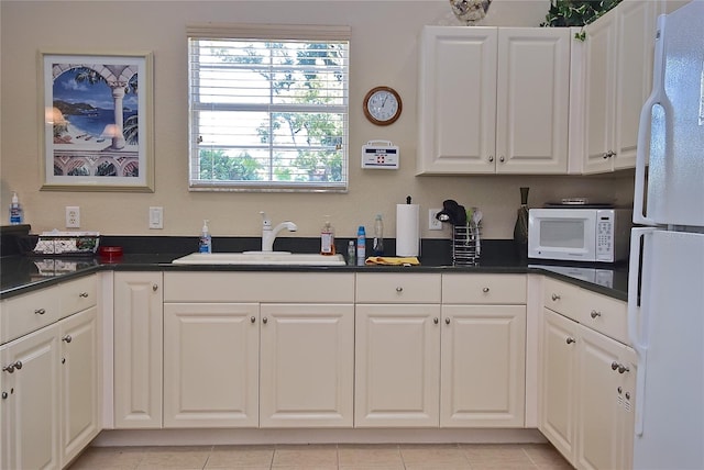 kitchen with white cabinets, light tile floors, white appliances, and sink