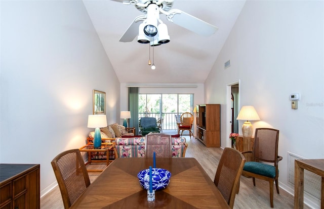 dining space featuring high vaulted ceiling, ceiling fan, and light wood-type flooring