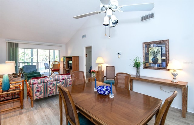 dining space with high vaulted ceiling, light hardwood / wood-style floors, and ceiling fan