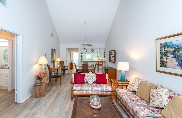 living room with high vaulted ceiling, ceiling fan, and light hardwood / wood-style flooring