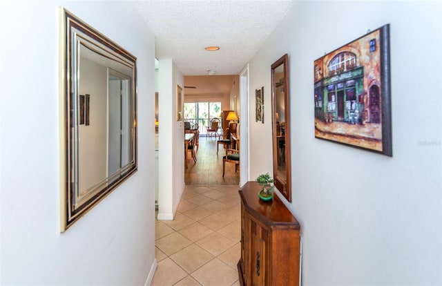 hallway with a textured ceiling and light tile floors