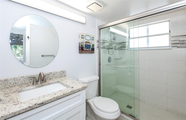 bathroom featuring plenty of natural light, a shower with door, toilet, and vanity