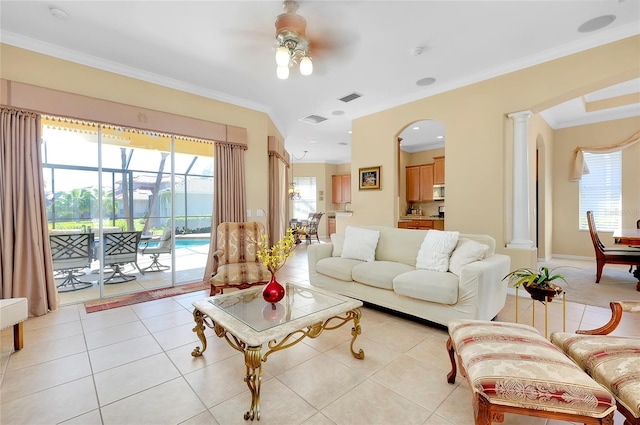 tiled living room with ceiling fan, ornamental molding, and decorative columns