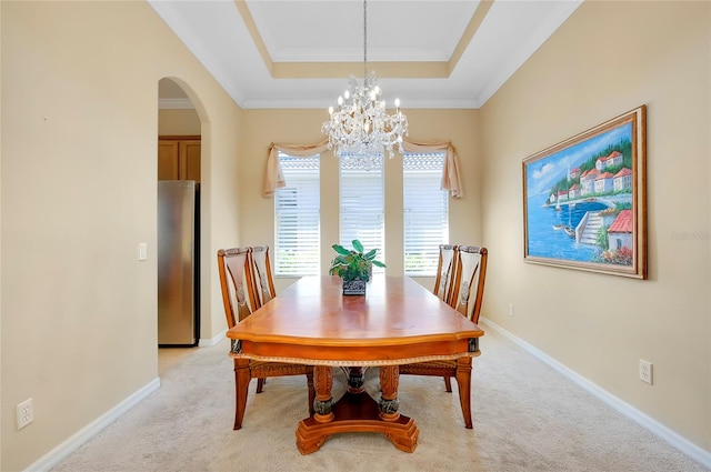 carpeted dining area featuring a tray ceiling and a chandelier