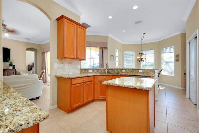 kitchen featuring light tile patterned flooring, a kitchen island, sink, crown molding, and light stone countertops