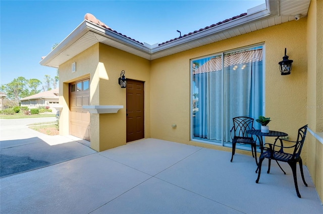 view of exterior entry with a garage and a patio area