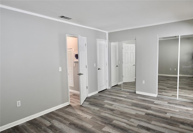 unfurnished bedroom with two closets and dark hardwood / wood-style flooring