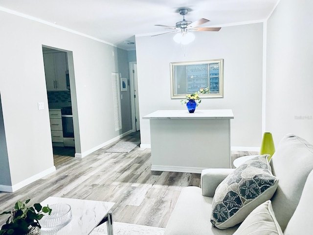 living room featuring ornamental molding, light wood-type flooring, and ceiling fan