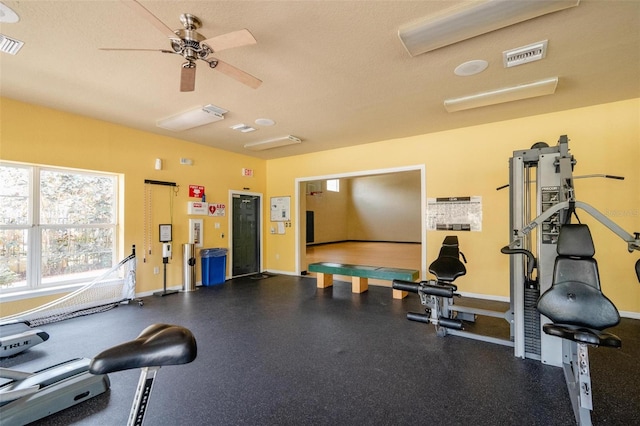 exercise room with ceiling fan and a textured ceiling