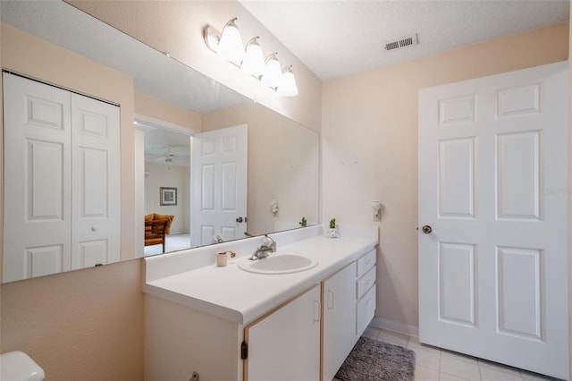 bathroom with tile flooring, large vanity, ceiling fan, and a textured ceiling