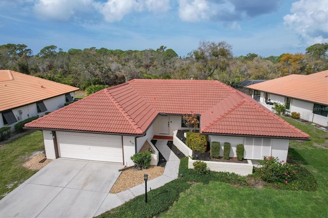 mediterranean / spanish house with stucco siding, a garage, driveway, a tiled roof, and a front lawn