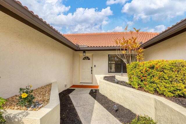 property entrance with a tiled roof and stucco siding