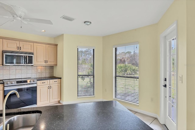 kitchen featuring appliances with stainless steel finishes, backsplash, light tile patterned floors, light brown cabinetry, and ceiling fan