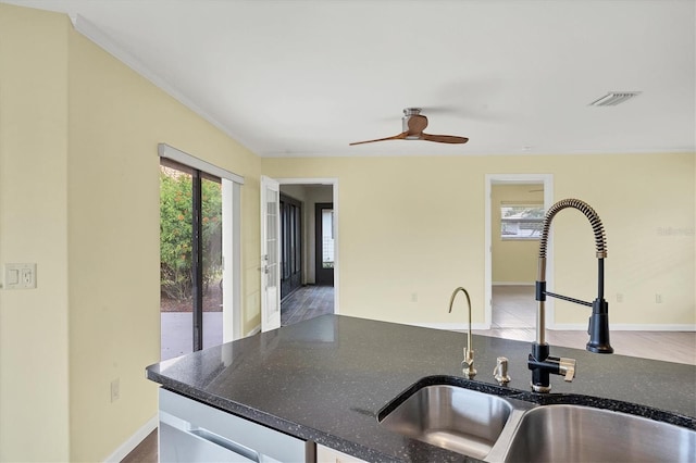 kitchen featuring sink, ceiling fan, light hardwood / wood-style floors, and dark stone counters