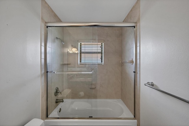 bathroom with shower / bath combination with glass door and toilet