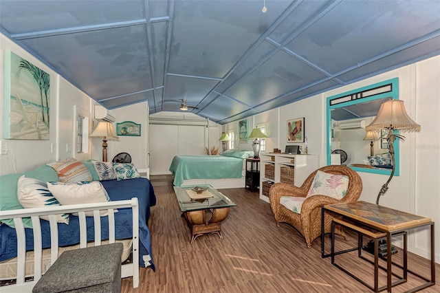 bedroom with a wall unit AC, hardwood / wood-style flooring, and vaulted ceiling