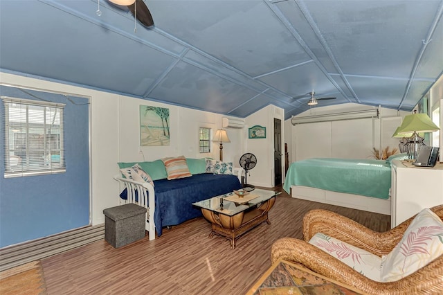 bedroom featuring lofted ceiling, wood finished floors, a ceiling fan, and a wall unit AC