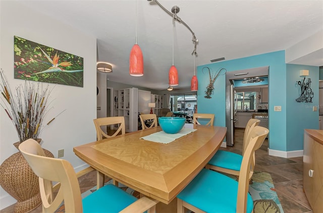 dining room featuring track lighting, baseboards, and visible vents