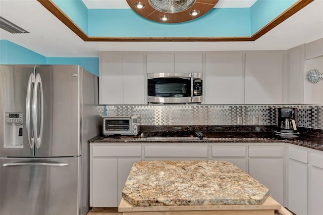 kitchen featuring white cabinetry, dark stone counters, tasteful backsplash, and stainless steel appliances