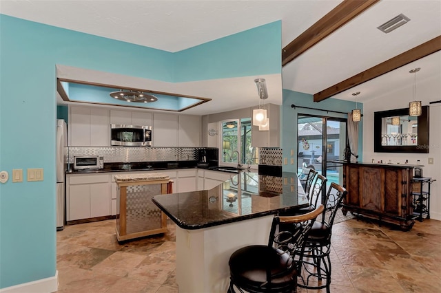 kitchen with pendant lighting, kitchen peninsula, stainless steel appliances, and white cabinets