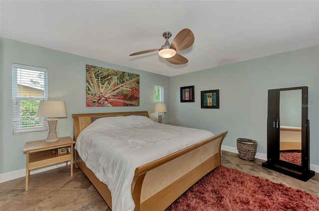 bedroom with light tile patterned floors, a ceiling fan, and baseboards