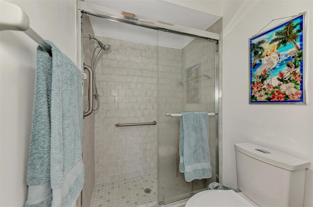 bathroom featuring toilet and a shower with door