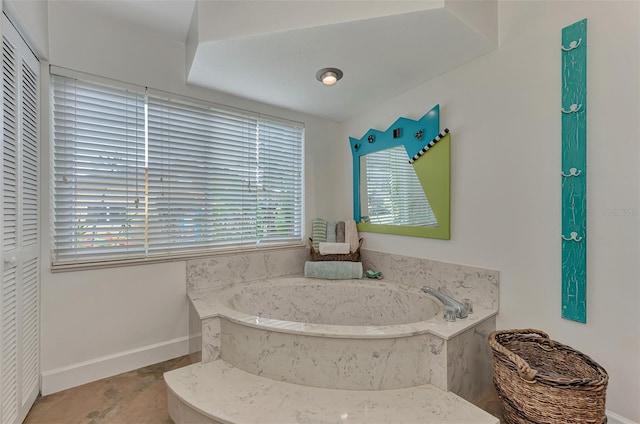 full bathroom with a bath and baseboards