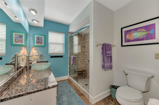 bathroom featuring vanity, toilet, a wealth of natural light, and a shower with door