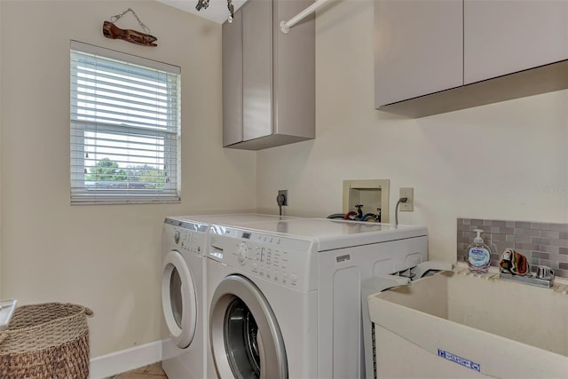 clothes washing area with washer and dryer, cabinets, and sink