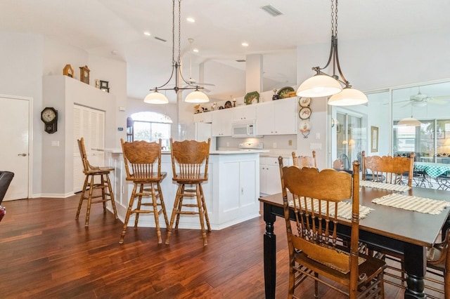 kitchen with pendant lighting, white appliances, high vaulted ceiling, and dark hardwood / wood-style floors