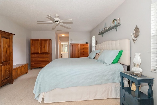 bedroom with light colored carpet, ensuite bath, ceiling fan, and a textured ceiling