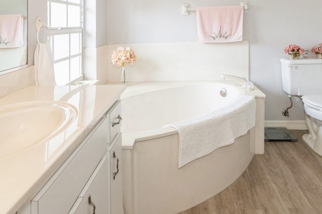 bathroom featuring hardwood / wood-style floors, large vanity, a bath to relax in, and toilet