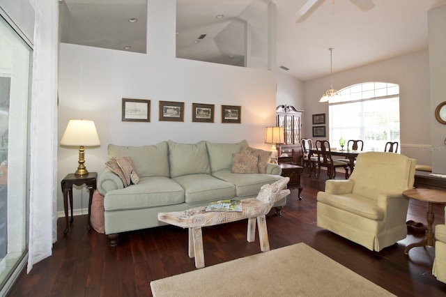 living room featuring dark wood-type flooring, high vaulted ceiling, and ceiling fan with notable chandelier