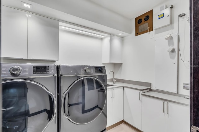 washroom featuring cabinets, sink, and washer and dryer