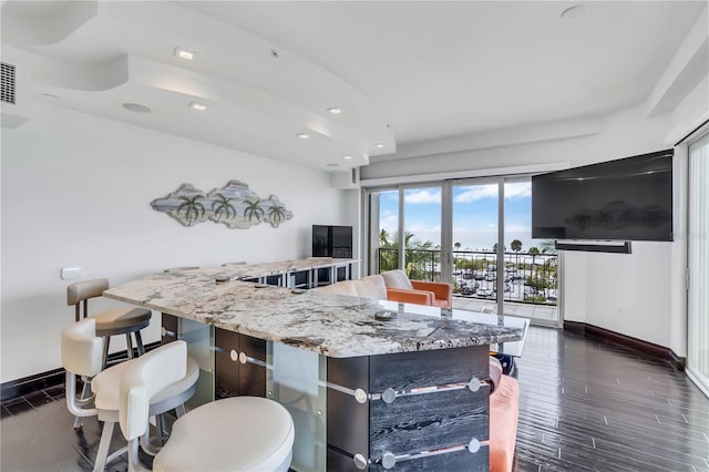 kitchen with light stone counters, dark hardwood / wood-style flooring, and a large island