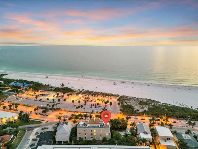 aerial view at dusk featuring a view of the beach and a water view