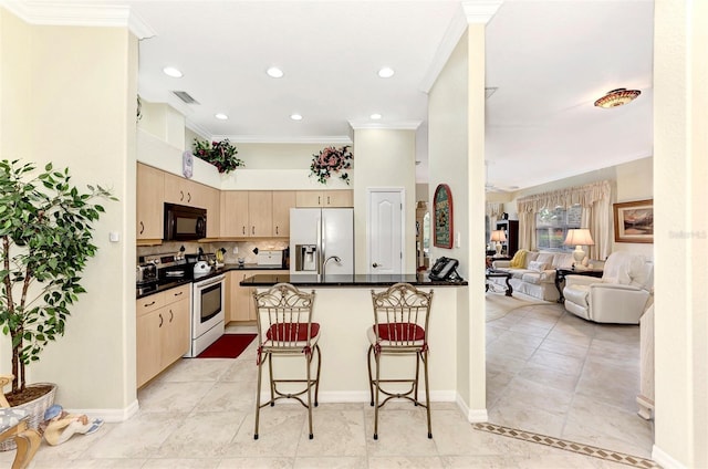 kitchen with stainless steel fridge with ice dispenser, light brown cabinets, electric stove, tasteful backsplash, and a breakfast bar area