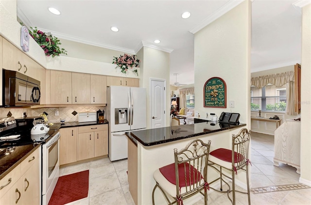 kitchen featuring a kitchen bar, light brown cabinets, white appliances, and light tile floors