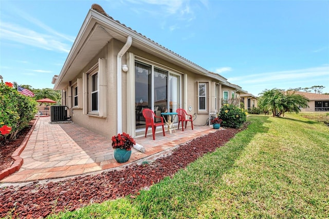 back of house with central AC unit, a patio area, and a yard