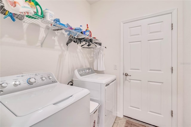 laundry room with washing machine and clothes dryer and light tile floors