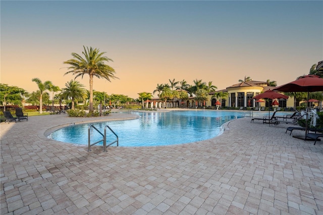 pool at dusk with a patio area