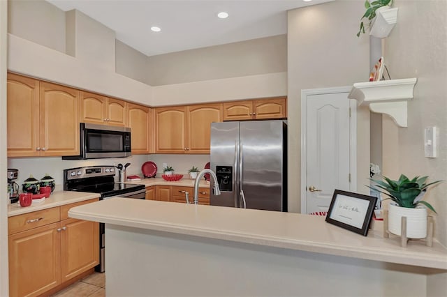 kitchen featuring light tile floors, kitchen peninsula, light brown cabinetry, appliances with stainless steel finishes, and sink