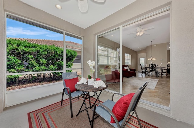 sunroom / solarium with ceiling fan with notable chandelier and lofted ceiling