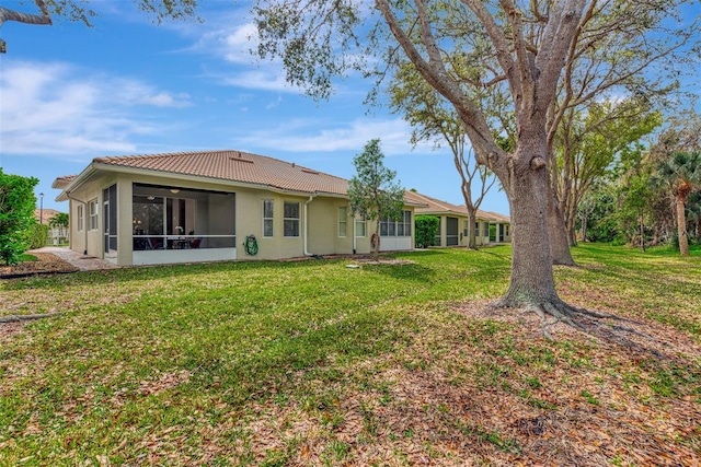 rear view of property featuring a lawn and a sunroom