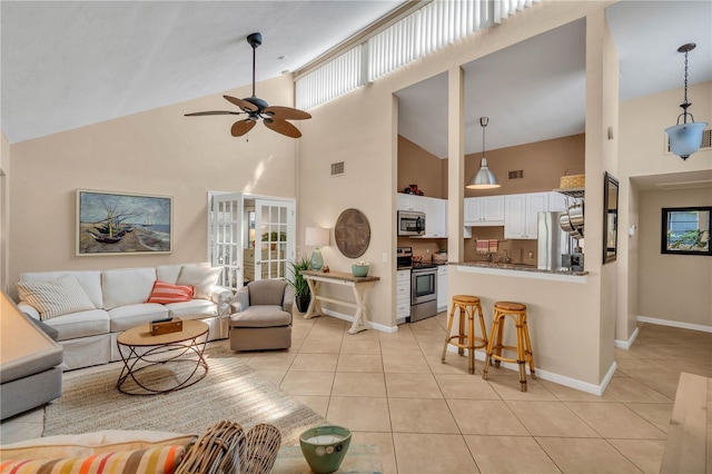 tiled living room featuring ceiling fan, high vaulted ceiling, and french doors