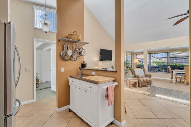 kitchen featuring stainless steel fridge, ceiling fan, white cabinets, and a towering ceiling