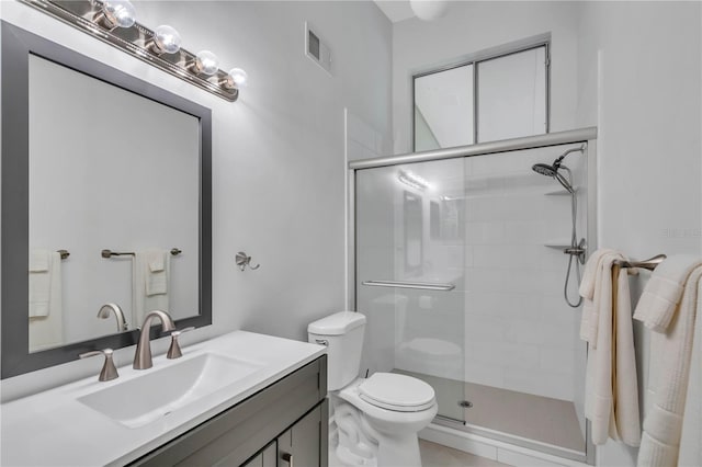 bathroom featuring toilet, a shower with shower door, and vanity