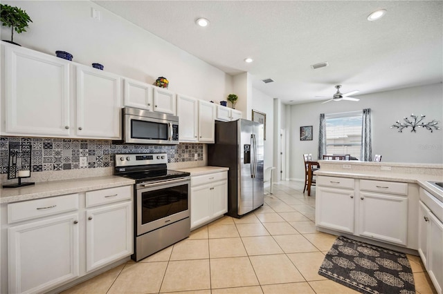 kitchen with appliances with stainless steel finishes, white cabinetry, ceiling fan, and light tile flooring